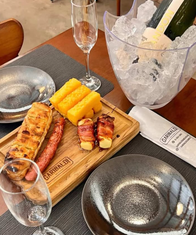 Tábua com linguiça, polenta frita e espetinhos de queijo com bacon servida na mesa do Garibaldi